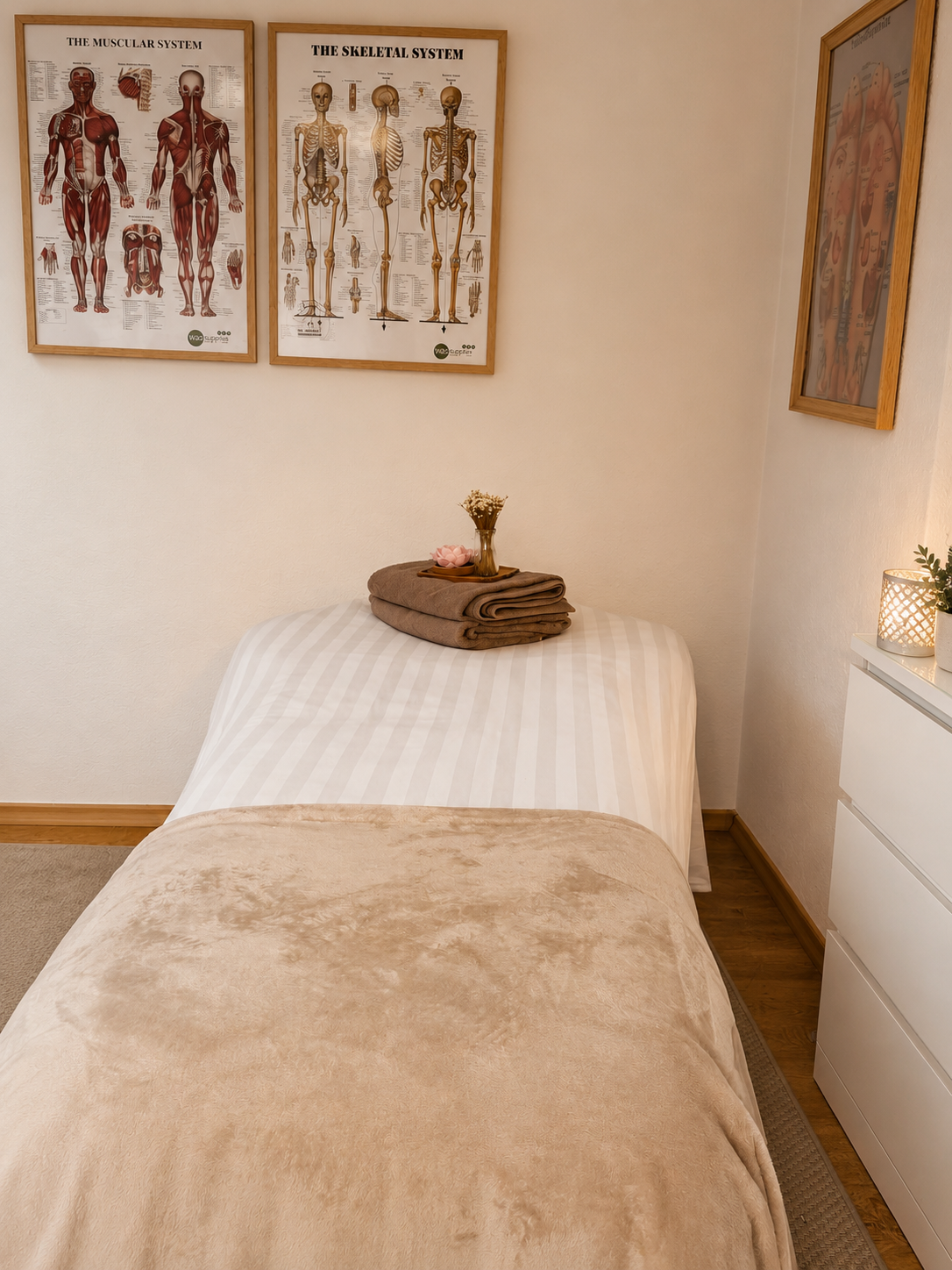 Behandelruimte met massagetafel en anatomieposters aan de muur